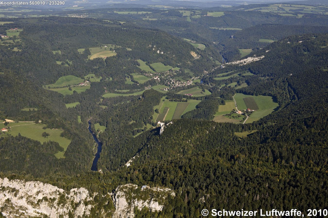 Arête des Sommêtres (Kalkfelswand im Vordergrund, Position 2'563'913.85, 1'231'833.13). Im Vordergrund Mitte auf der Krete: Ruine Spiegelberg (1079 m). Siedlung Bildmitte: Goumois (F; 493 m) . Im Tal: Le Doubs, ganz vorne im Bild, wo der Doubs sichtbar wird: Le Theusseret (507 m).
